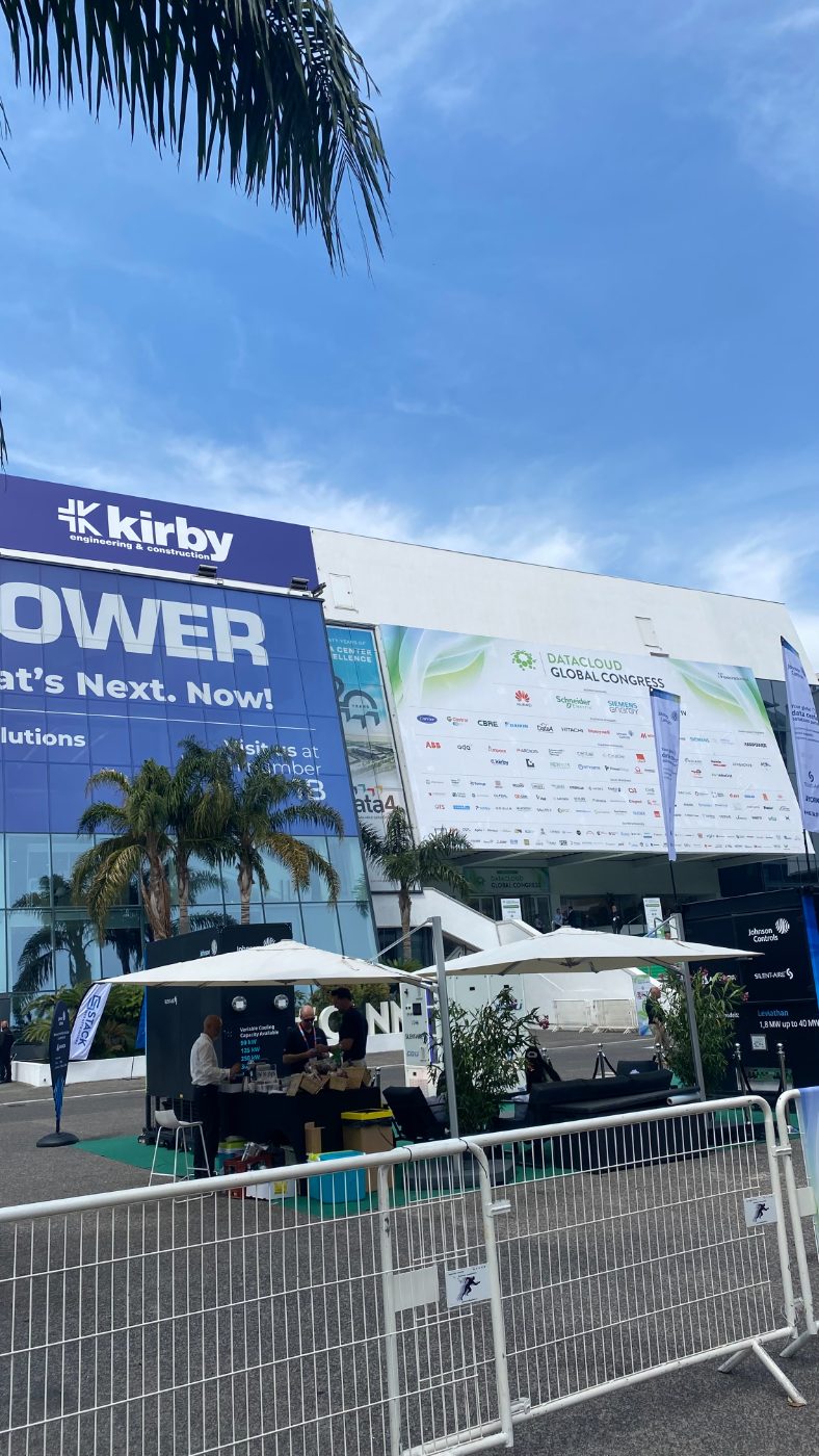 Day one. The welcome board, the Kirby and Karpower wraps, and the sponsor wall that reads like a list of who owns European infrastructure.