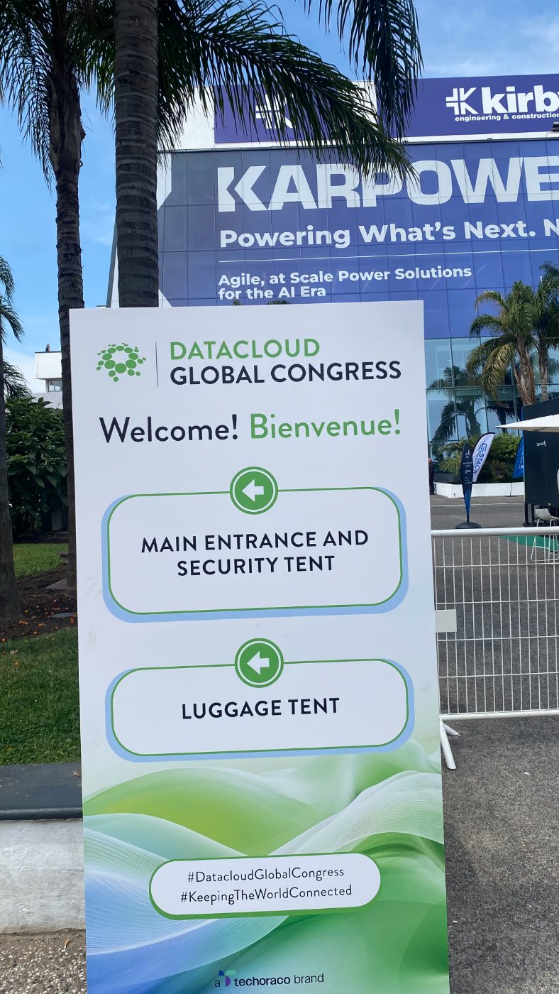 Day one. The welcome board, the Kirby and Karpower wraps, and the sponsor wall that reads like a list of who owns European infrastructure.